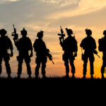 oddział na tle zachodzącego słońca